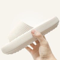 Hand holding cream white Cloud Slide showing sole texture and strap detail