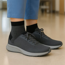 Load image into Gallery viewer, Black Foot & Ankle Sleeve Compression Sock worn inside grey sneaker with blue scrub pants