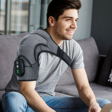 Load image into Gallery viewer, Smiling young man seated on grey sofa wearing heated compression shoulder brace with LED display