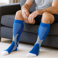 Man seated on grey sofa wearing blue grey LegEase Compression Socks