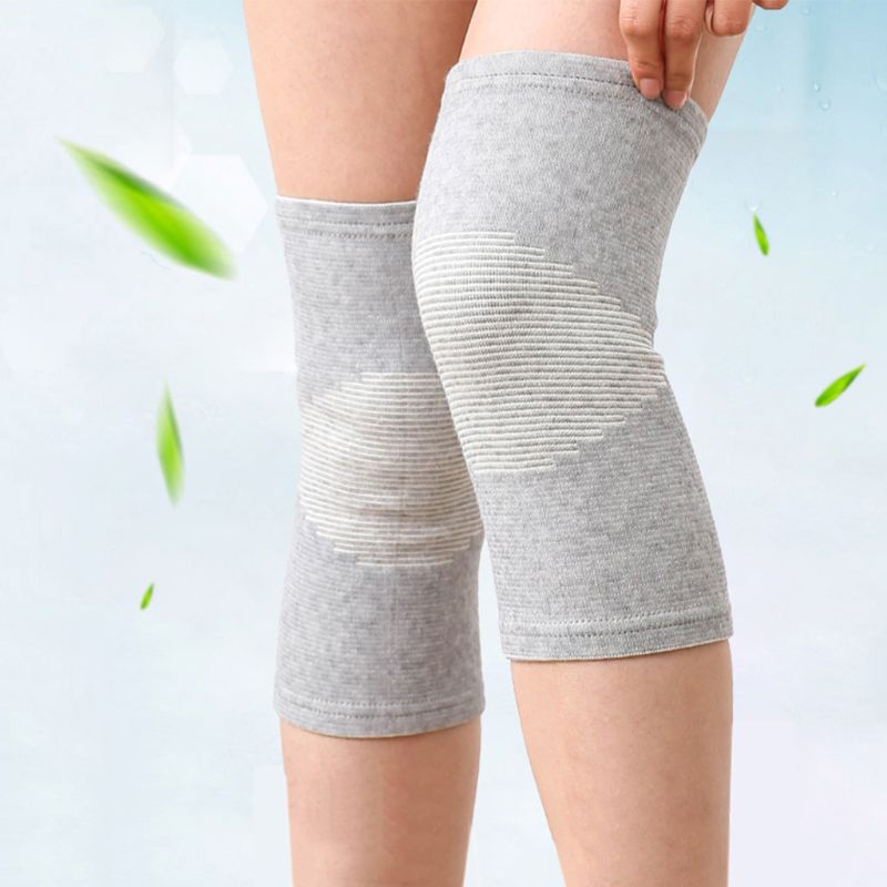 Pair of grey bamboo knee support sleeves worn on both legs with green leaves in background
