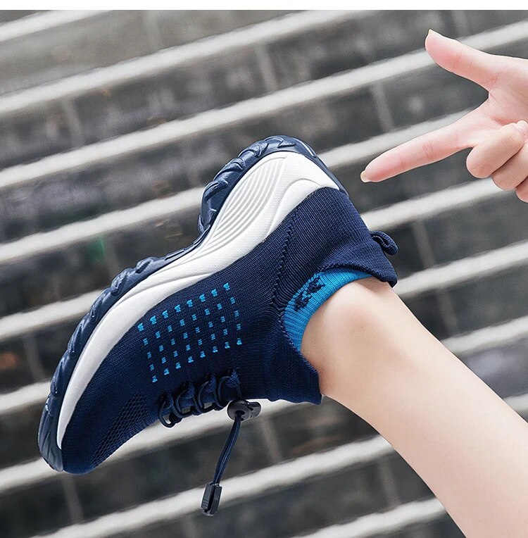 Hand holding navy blue orthopaedic comfort shoe showing sole and knit upper