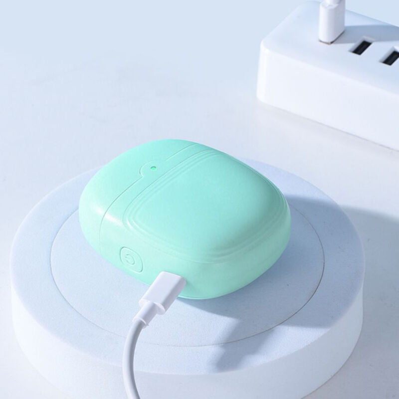 Mint green electric nail clipper charging via USB cable on a white stand near a power board