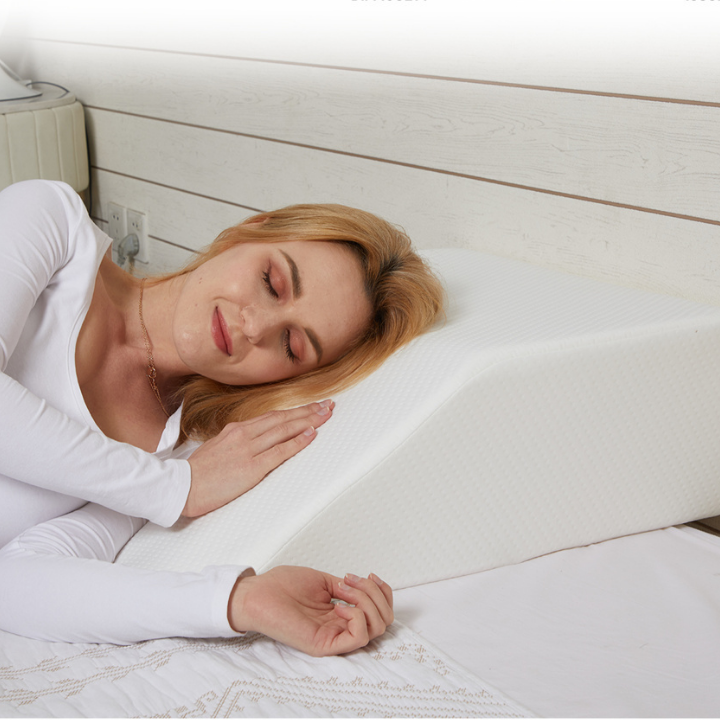 Woman resting her head on a wedge pillow while lying on her side in bed