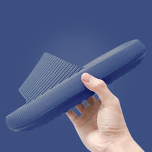 Load image into Gallery viewer, Hand holding navy blue Cloud Slide showing textured sole, side angle
