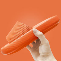 Hand holding orange Cloud Slide showing ribbed upper and sole detail
