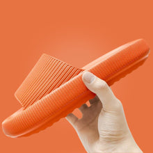 Load image into Gallery viewer, Hand holding orange Cloud Slide showing ribbed upper and sole detail
