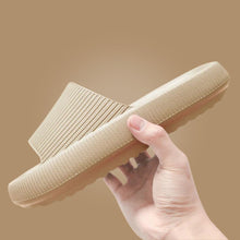 Load image into Gallery viewer, Hand holding beige Cloud Slide showing ribbed strap and sole texture
