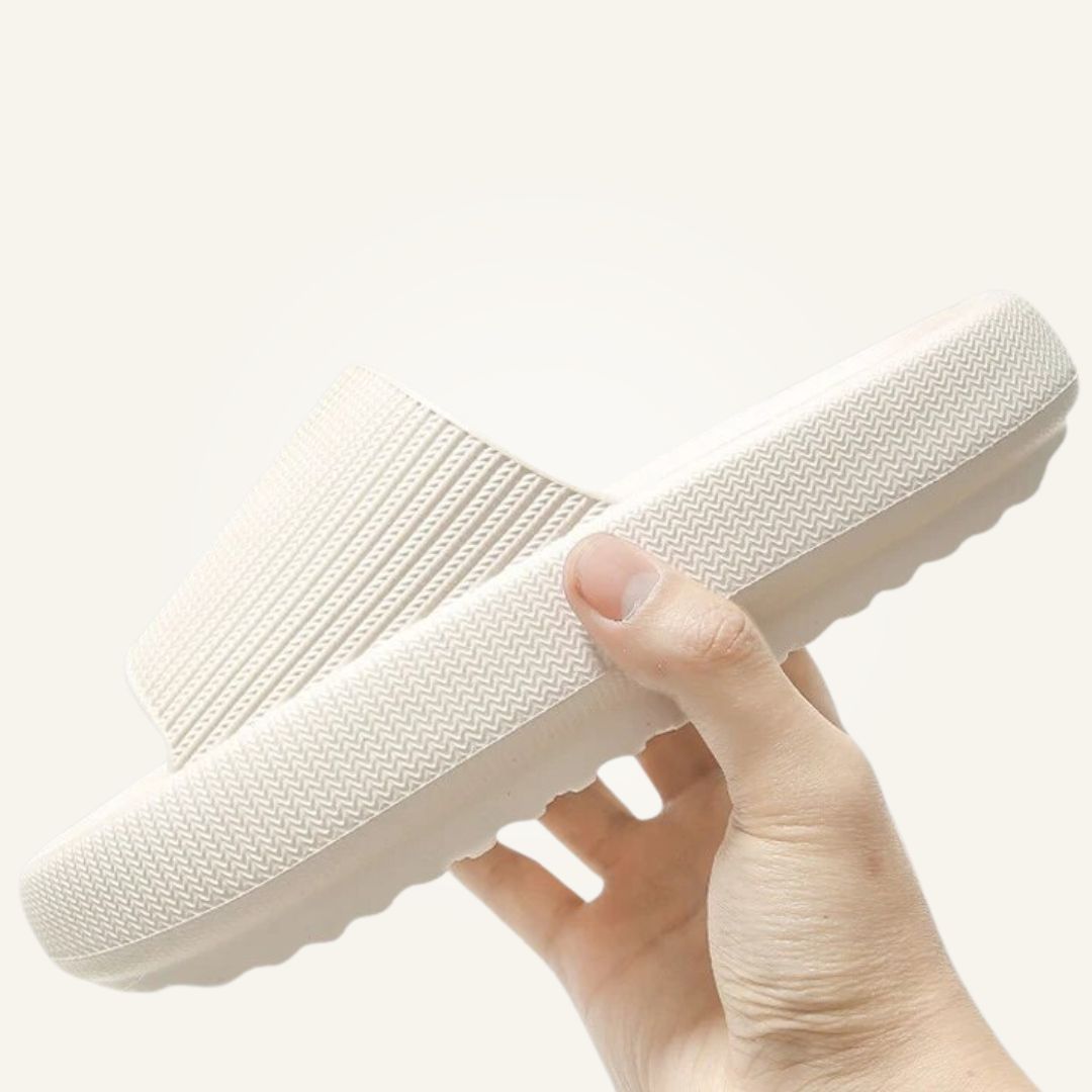 Hand holding cream white Cloud Slide showing sole texture and strap detail