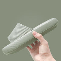 Hand holding sage green Cloud Slide showing ribbed upper and chunky sole