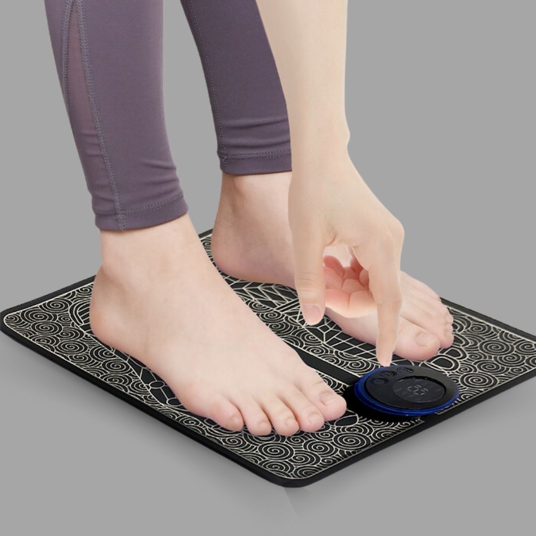 Person in grey leggings pressing control button on black EMS Foot Massage Mat