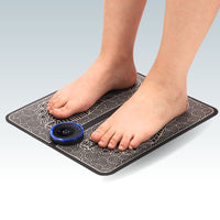 Bare feet standing on black EMS Foot Massage Mat with glowing blue control unit