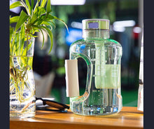Load image into Gallery viewer, Green hydrogen water bottle generator beside plant vase on timber surface
