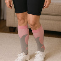 Person wearing pink grey LegEase Compression Socks with white sneakers indoors