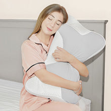 Load image into Gallery viewer, Woman in pink pyjamas hugging the neck and shoulder support pillow while seated on a bed
