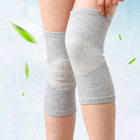 Pair of grey bamboo knee support sleeves worn on both legs with green leaves in background