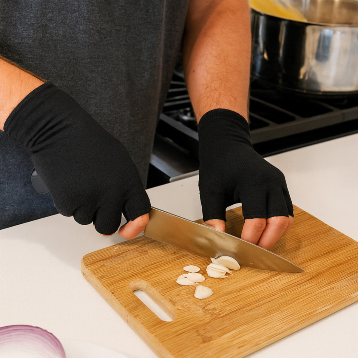 Person wearing black Therapeutic Heat Gloves chopping garlic in kitchen