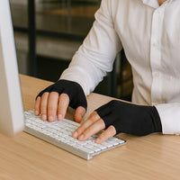Person wearing black Therapeutic Heat Gloves typing on white keyboard