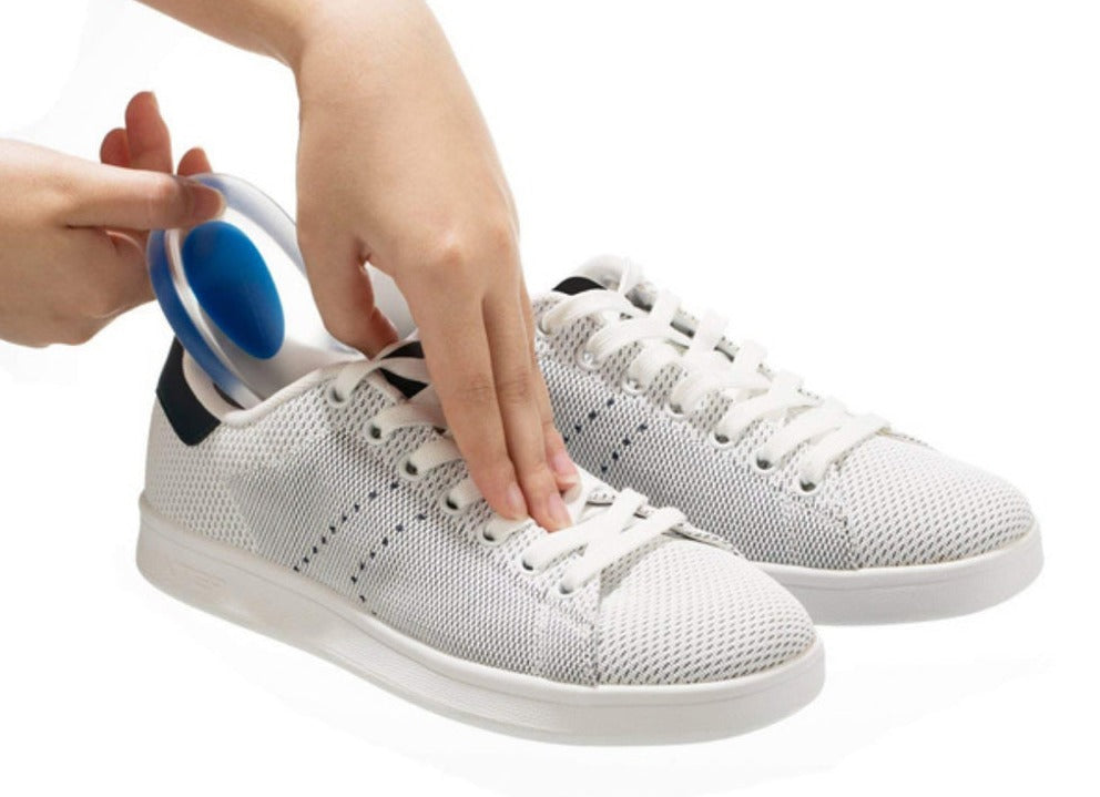 Hand inserting a clear silicone gel heel cup into a white mesh sneaker