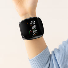 Load image into Gallery viewer, Close-up of wrist blood pressure monitor on raised arm showing 120/80 mmHg on large LED display
