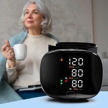 Load image into Gallery viewer, Black wrist blood pressure monitor showing 120/80 mmHg reading, with older woman holding a cup of tea in the background
