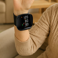 Wrist blood pressure monitor on a raised arm in beige knitwear displaying 120/80 mmHg SYS, DIA and pulse readings