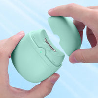 Two hands opening the mint green electric nail clipper to reveal the internal blade compartment